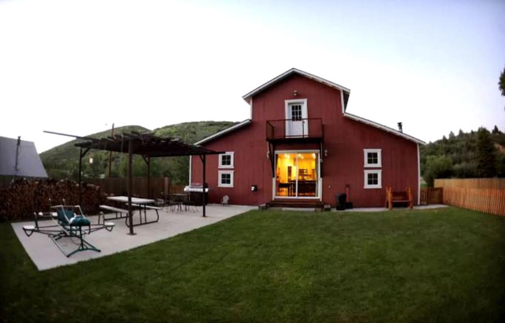 a red house with chairs and tables in a yard at Luxurious Pet-Friendly Vacation Rental close to Mirror Lake in Kamas, Utah in Kamas