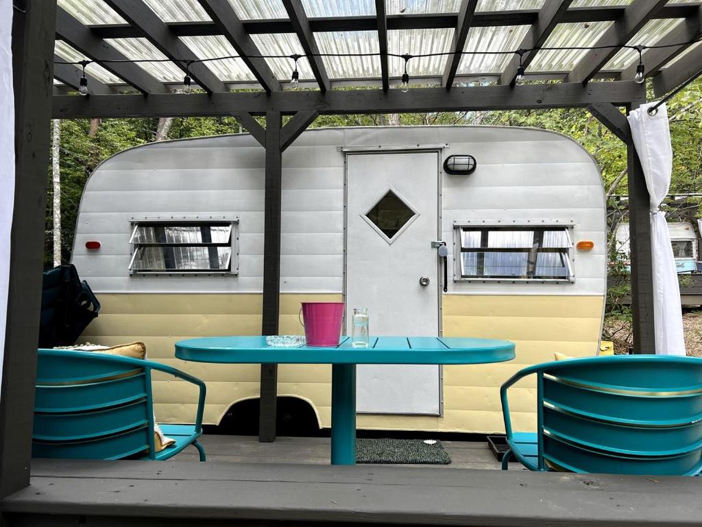 a table and chairs in front of a trailer at Remote Vintage Camper Rental for Adult-Only Retreat in Franklin, North Carolina in Franklin