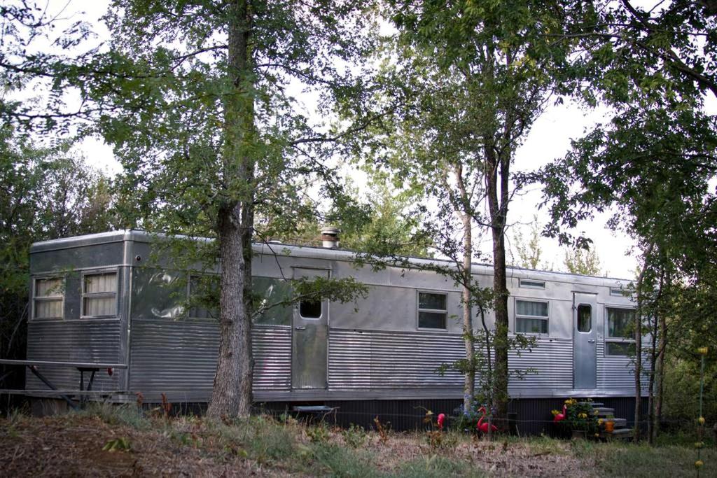 a silver train car parked next to some trees at Stunning Vintage Trailer for a Glamping Getaway in Denison, Texas in Pottsboro