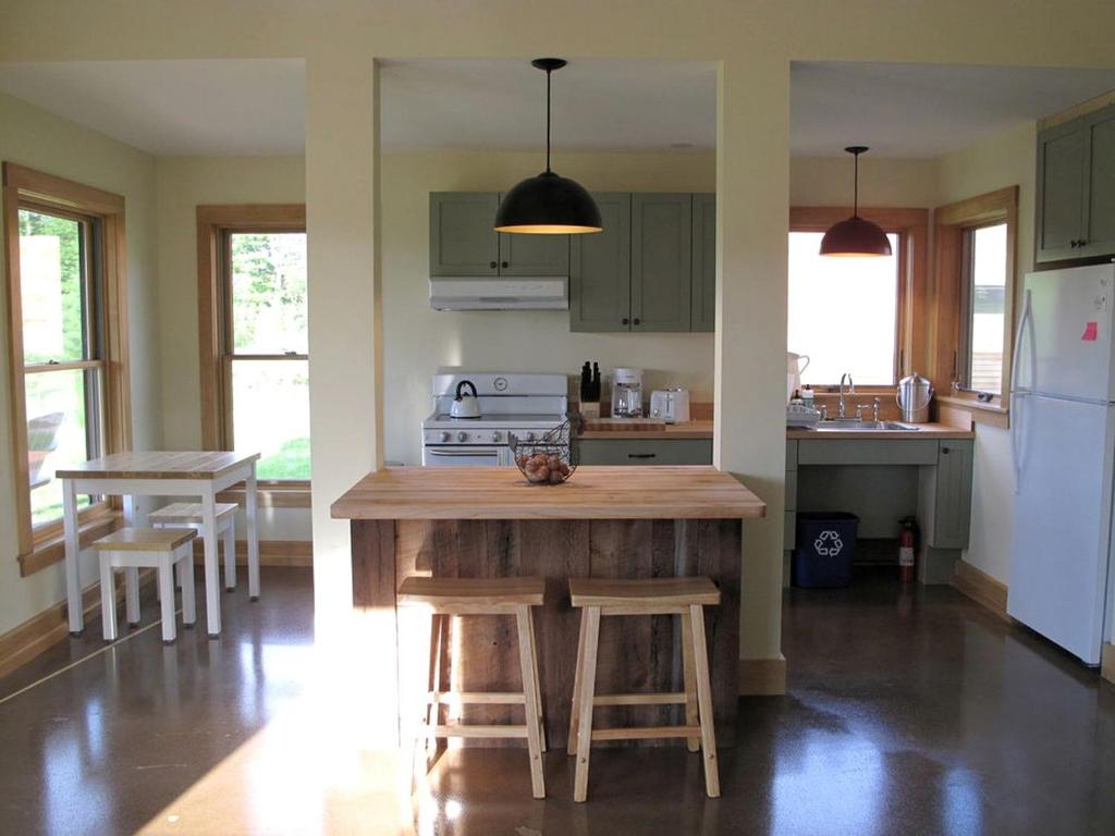 a kitchen with green cabinets and a island with stools at Elegant Cabin Rental on a Hillside Farm in Hartland, Vermont in Sheddsville