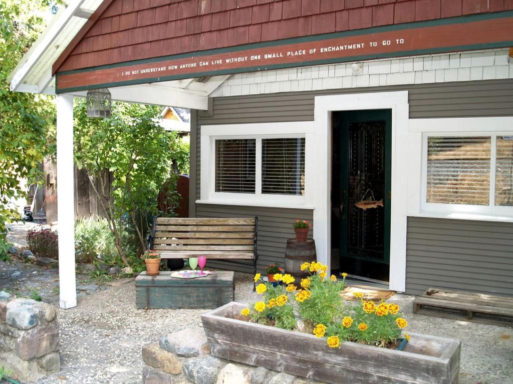 eine Veranda eines Hauses mit einer Bank und Blumen in der Unterkunft Spectacular Riverside Getaway Cabin with Claw Foot Bathtub in Castella, California in Dunsmuir