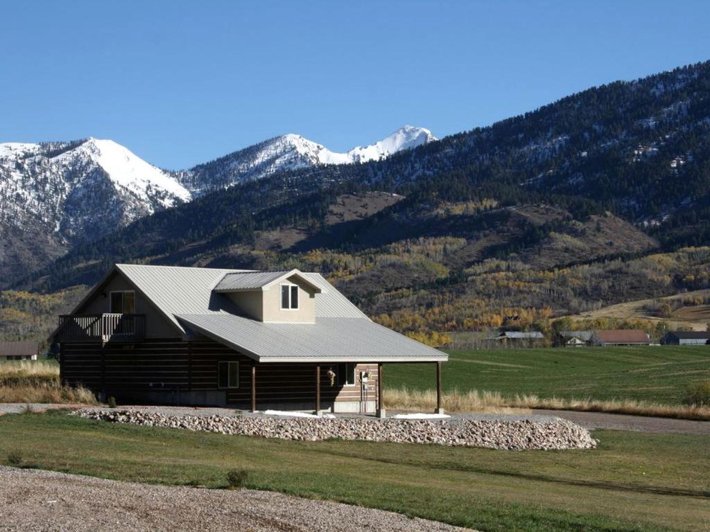 une cabane en rondins avec des montagnes en arrière-plan dans l'établissement Charming Vacation Rental for Large Groups near Yellowstone National Park, Wyoming, à Thayne