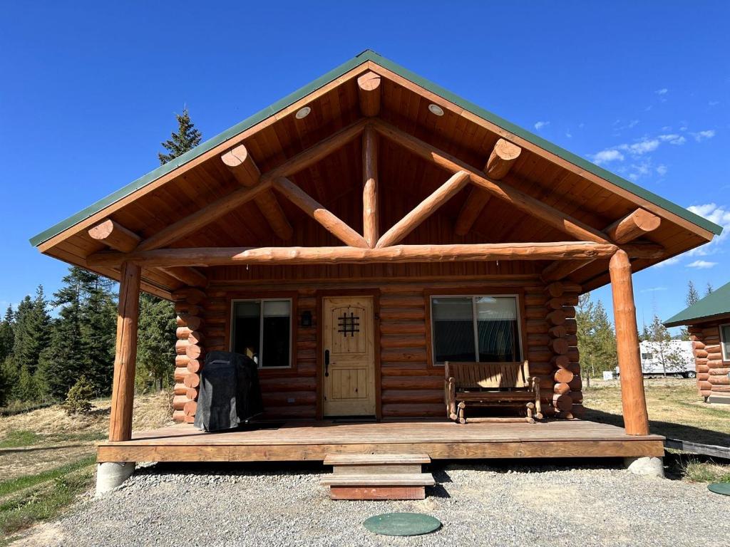 a log cabin with a porch and a bench at Cozy 1-Bedroom Log Cabin with Full Kitchen & Wi-Fi | Bonners Ferry, Idaho Retreat in Bonners Ferry