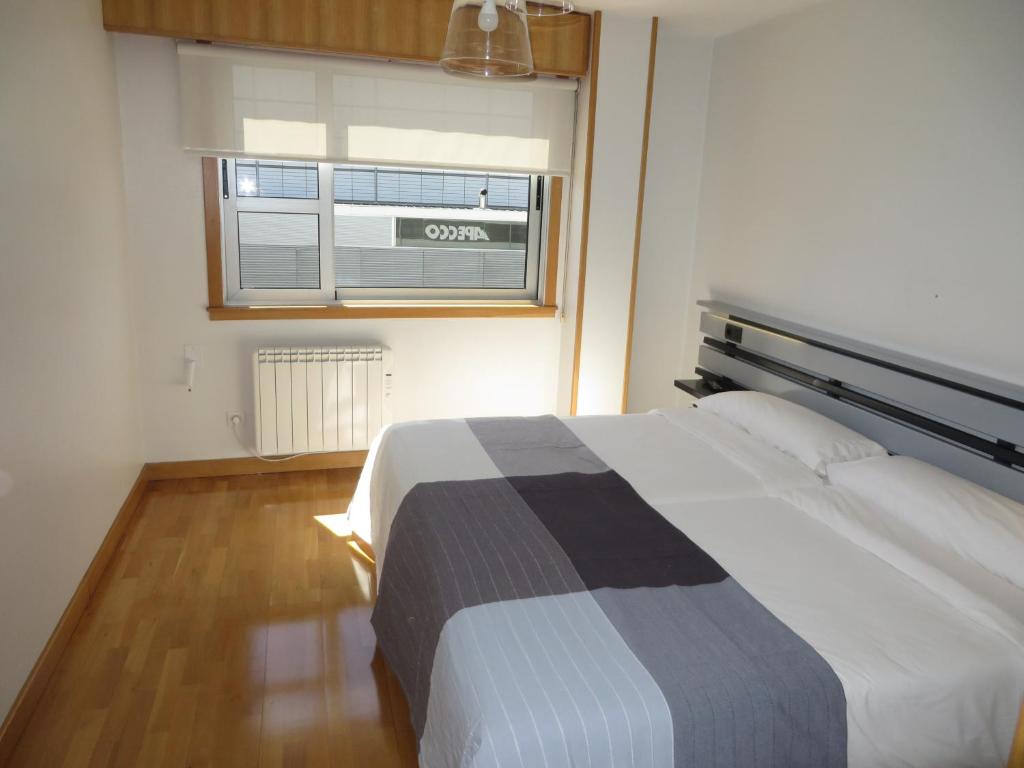 1 dormitorio con 1 cama grande y ventana en Toctoc Rooms, en A Coruña