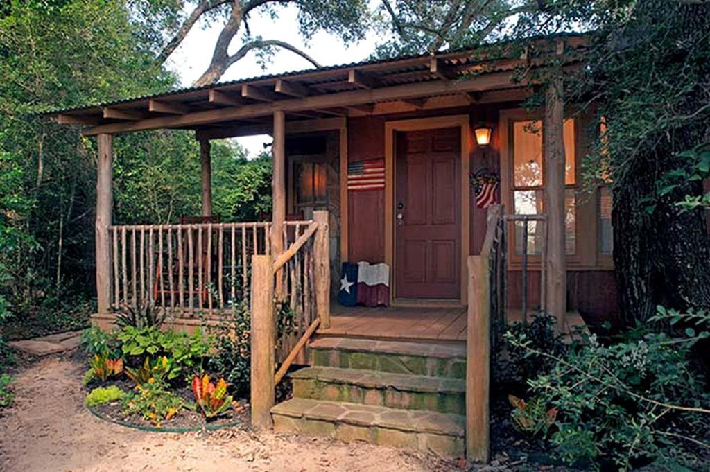a small house with a porch and an american flag at Secluded Cabin Rental with Jacuzzi for Romantic Weekend Getaway near Austin, Texas in Cat Spring