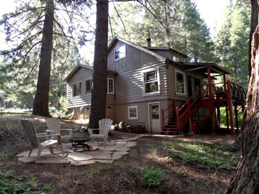 a house in the woods with chairs and a tree at Cozy Vacation Cottage Rental near Lassen Volcanic National Park, Northern California in Shingletown