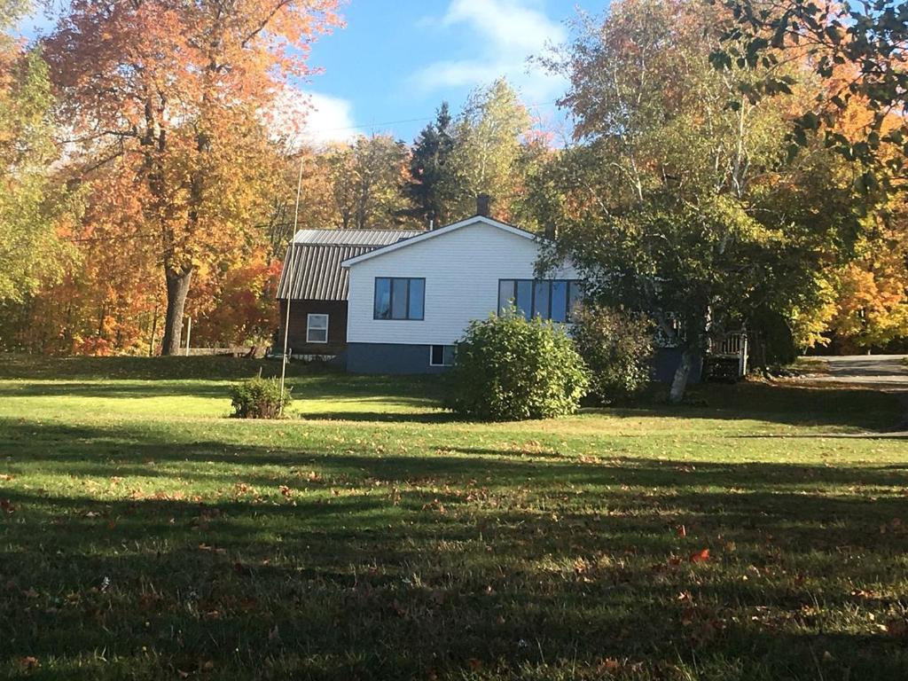 a white house in the middle of a field at Embrace Nature in this Breathtaking Cottage in Portage Lake, Maine in Portage Lake Municipal Seaplane Base