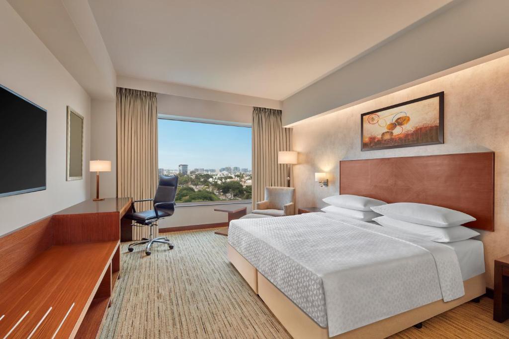 a hotel room with a bed and a large window at Four Points by Sheraton Hotel and Serviced Apartments Pune in Pune