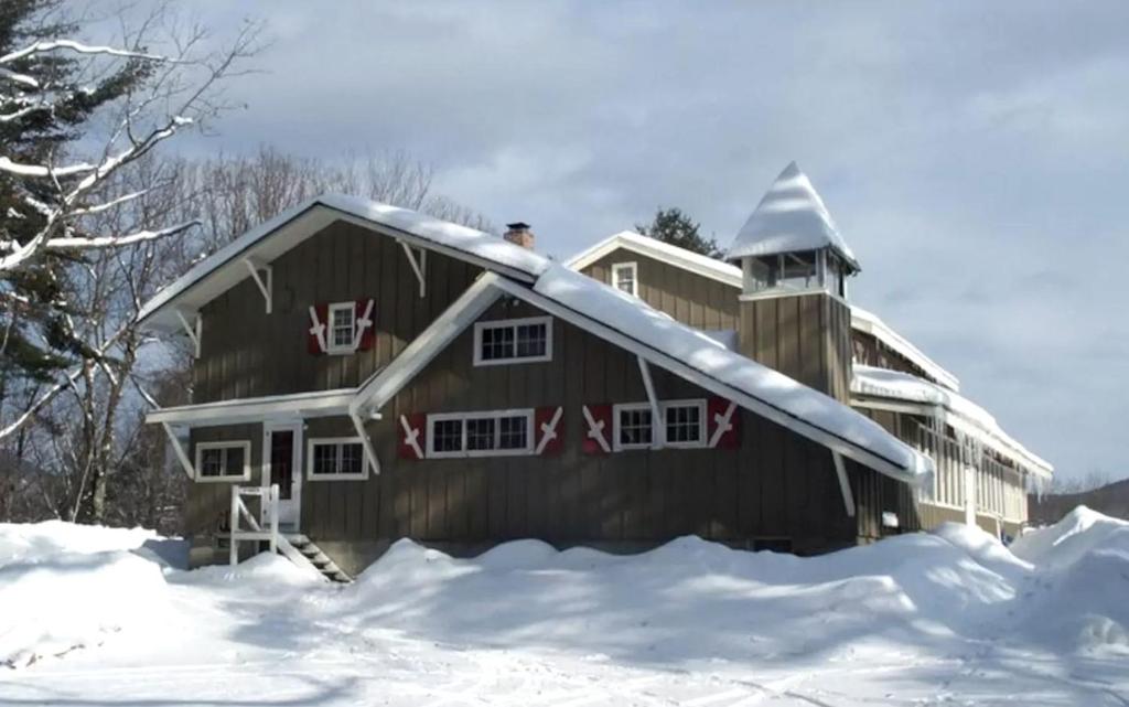 a house with a snow covered roof in the snow at Spacious Vacation Rental for Large Groups in the White Mountains near Plymouth, New Hampshire in Plymouth