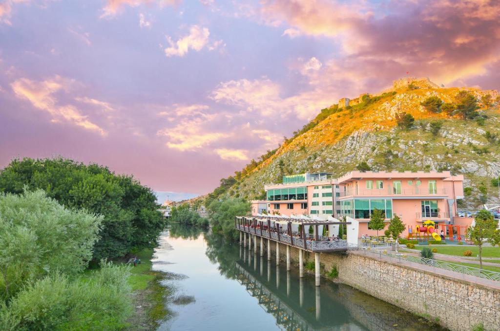 un fiume con edifici sul fianco di una montagna di Luani A Hotel a Shkodër