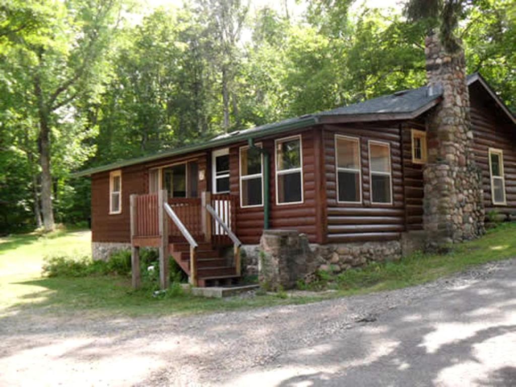 a log cabin with a porch and stairs to it at Enchanting Woodland Cabin Perfect for a Family Getaway on Moose Lake, Wisconsin in New Post