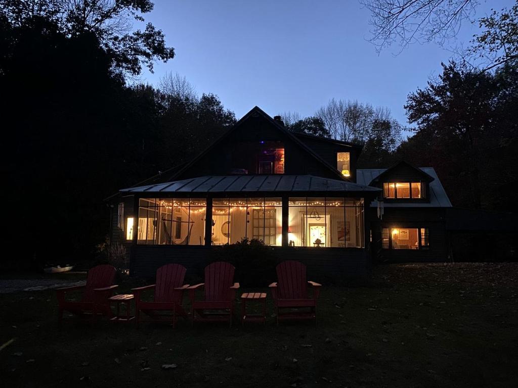 a house with chairs in front of it at night at Cozy Cottage Rental with Lake Views near Okemo State Forest, Vermont in Tyson