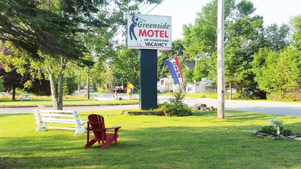a sign for a motel with two chairs in the grass at Greenside Motel in Saint Andrews