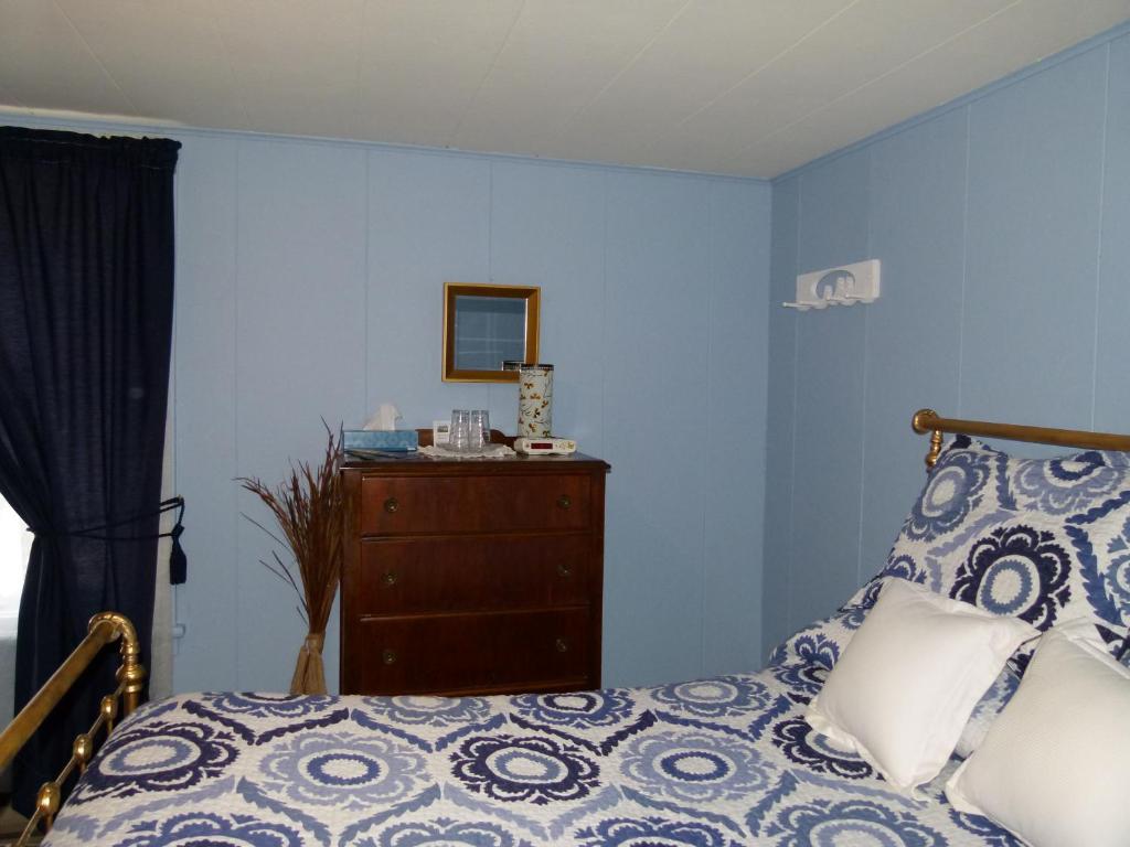 a bedroom with blue walls and a bed and a dresser at La Maison entre Mer Montagnes in Cap-Chat