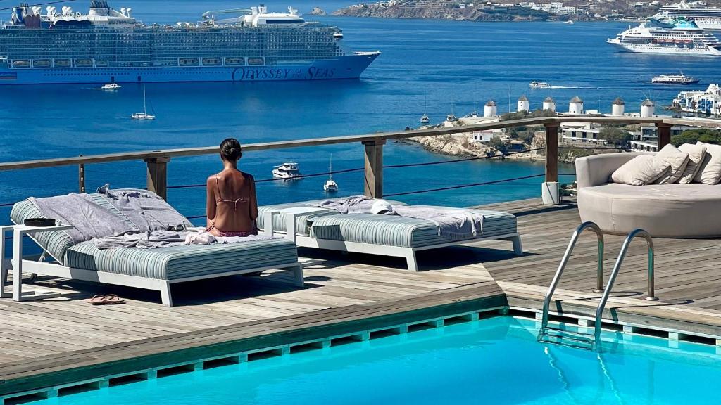 two beds on a deck next to a pool with a cruise ship at Tharroe of Mykonos Boutique Hotel in Mýkonos City