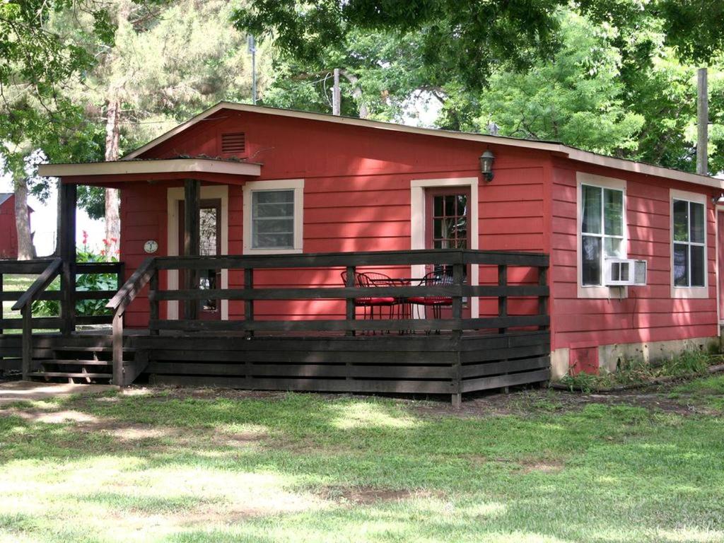a red tiny house with a porch and a fence at Spacious 10-Person Cabin Rental on Lake Dunlap near Austin, Texas in Schumannsville
