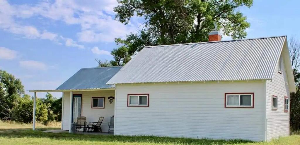 a white tiny house with a gray roof at Secluded Cottage on East Ash Creek near Fort Robinson State Park, Nebraska in Whitney
