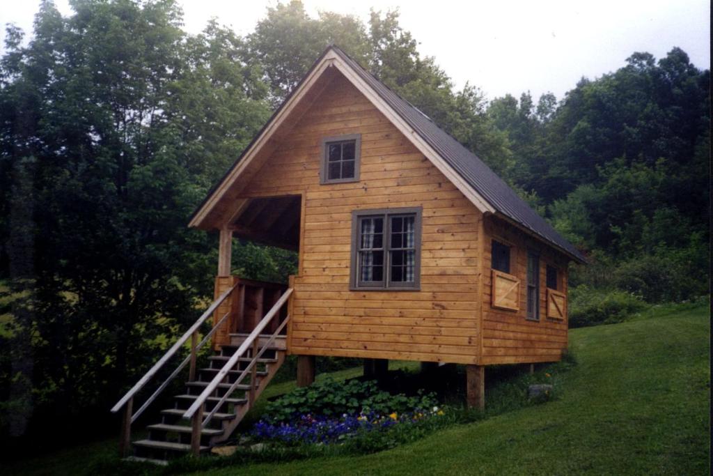 a log cabin with a staircase in a yard at Rustic Vacation Rental on a Beautiful Working Farm in Royalton, Vermont in South Royalton