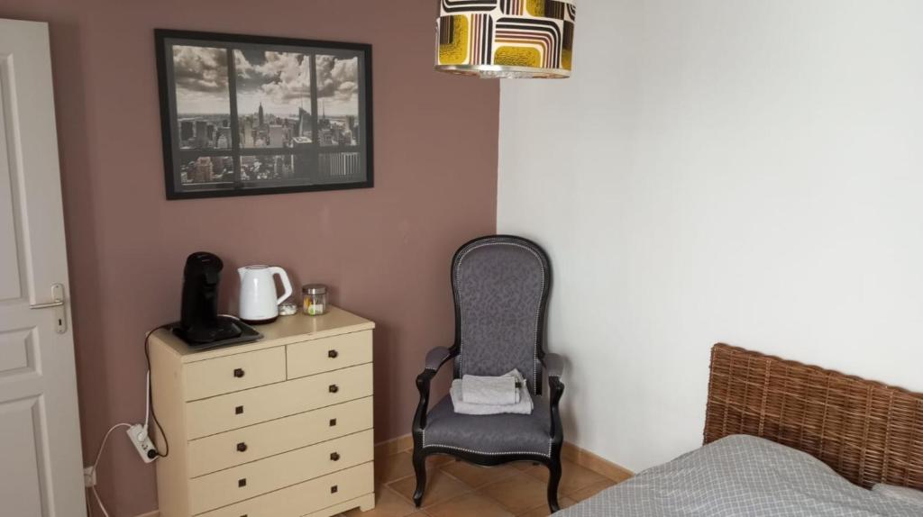 a bedroom with a chair and a dresser at Étage prive avec Chambre, salle de bain, terrasse in Avignon