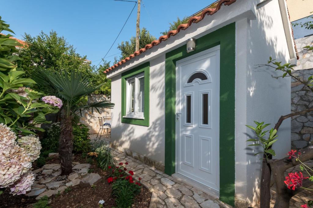 une petite maison avec une porte verte et blanche dans l'établissement Mito Rooms and Apartments, à Trogir