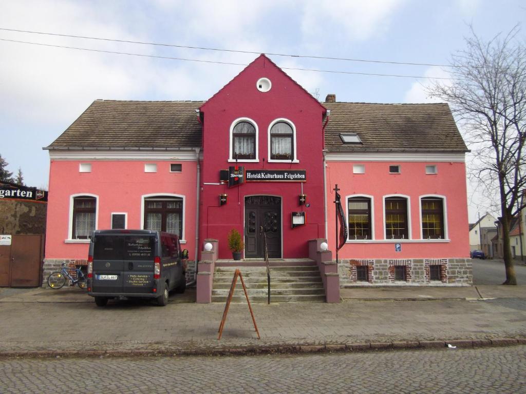 a pink house with a truck parked in front of it at Hotel Kulturhaus Felgeleben in Schönebeck