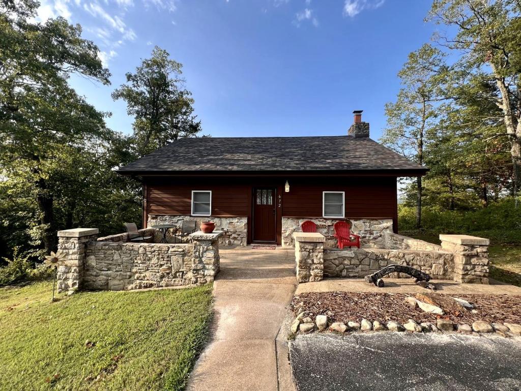 a small house with a stone wall in front of it at Cozy Cabin Rental near Table Rock Lake in the Ozark Mountains, Missouri in Hollister
