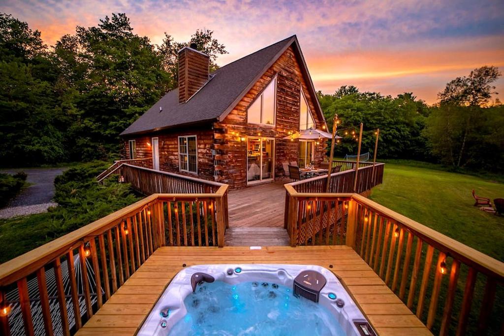 a hot tub on the deck of a house at Incredible New York Cabin with a Spa and Movie Theater in Livingston Manor