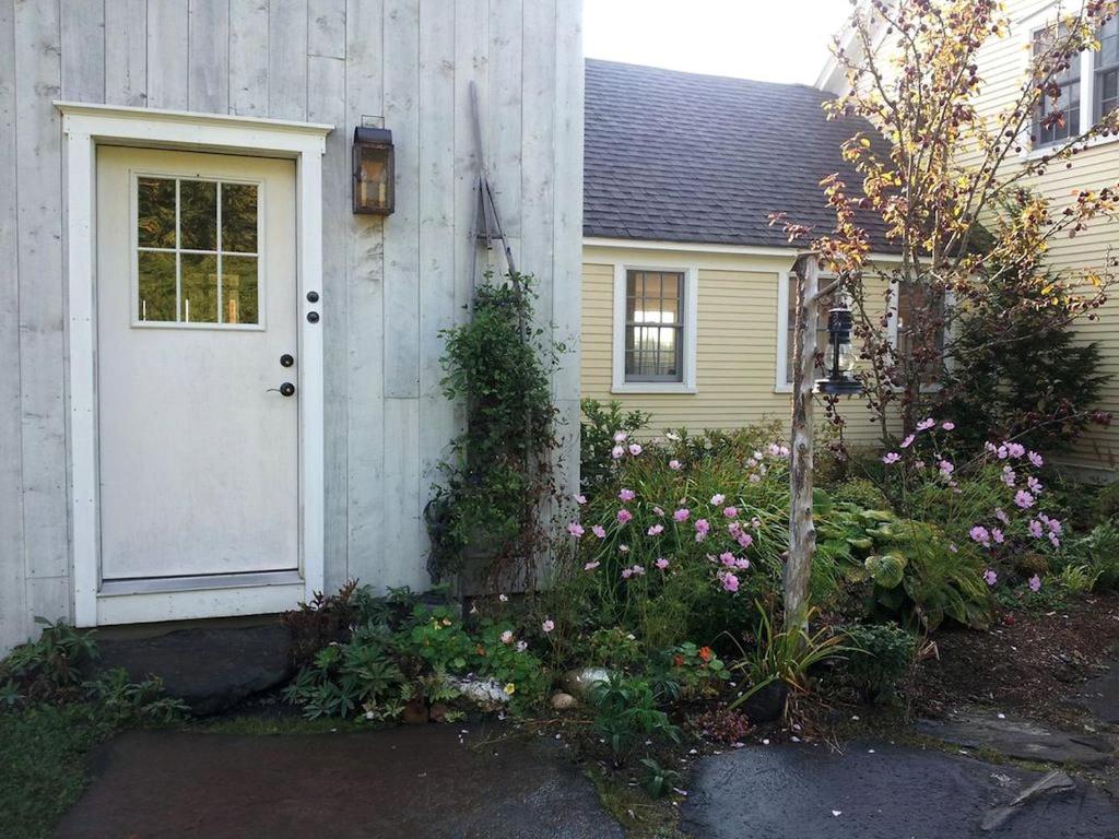 a house with a white door and some flowers at Idyllic Cottage Rental near Mount Mansfield State Forest, Vermont in Hardwick