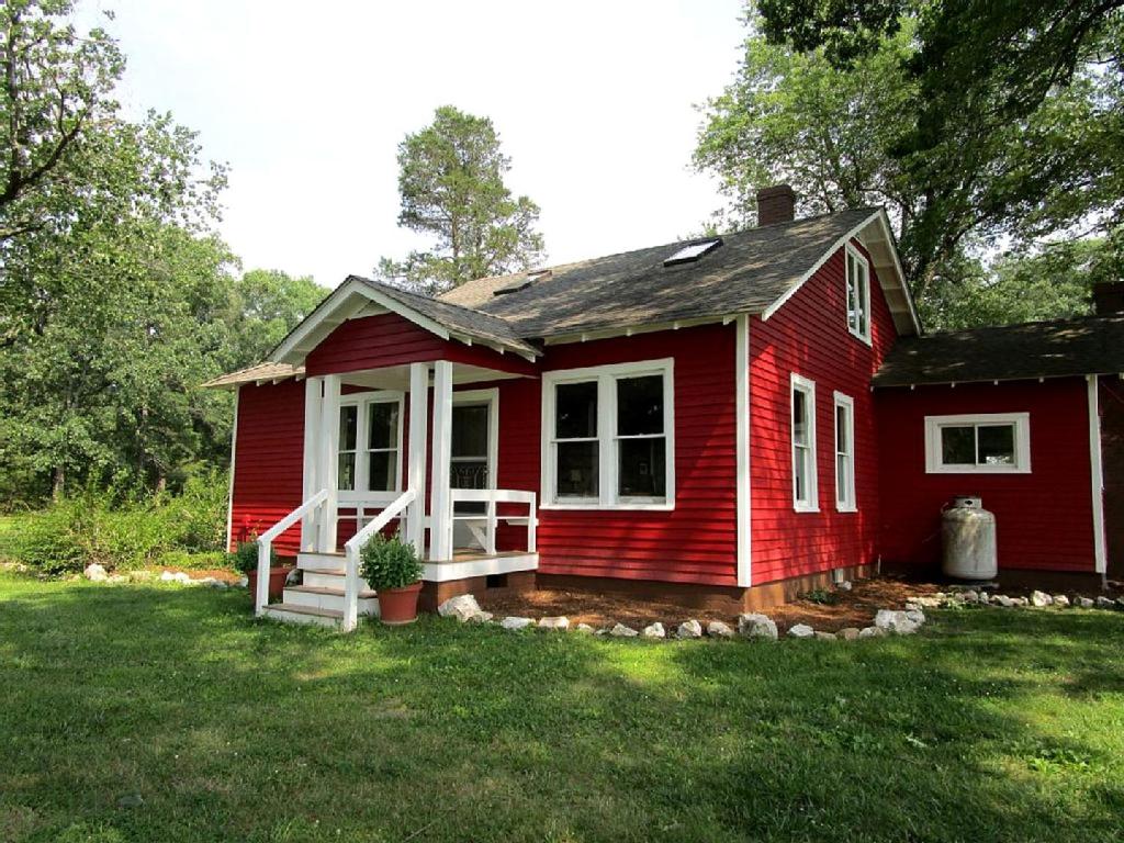 a red house with a potted plant in front of it at Serene Countryside Cottage Rental with Screened Porch near Charlottesville, Virginia in Byrd Mill