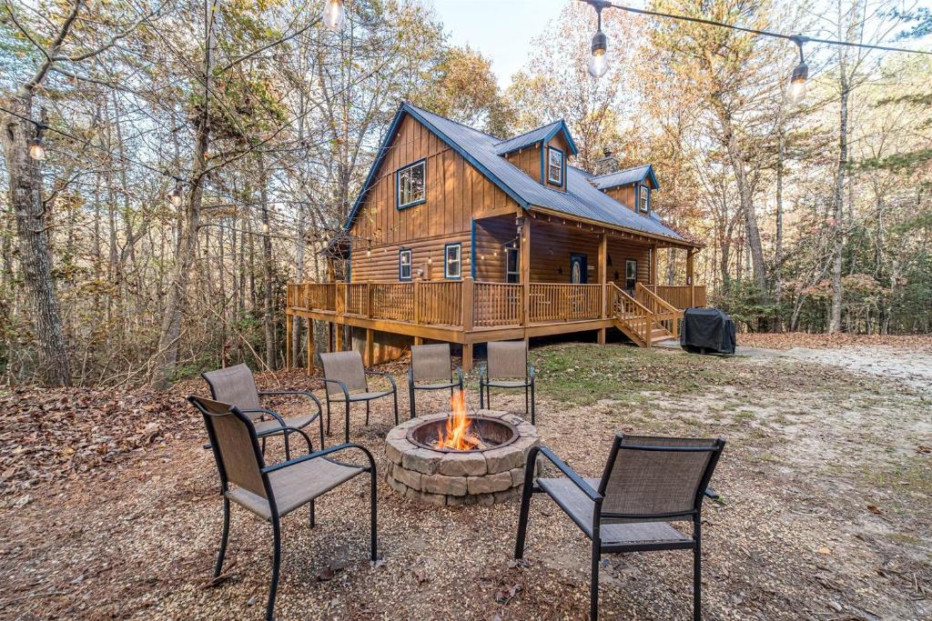 a cabin with chairs and a fire pit in front of it at Secluded Cabin with Hot-tub and Fire Pit in Cleveland, Georgia in Kinseytown