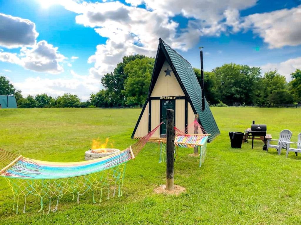 une petite tente avec un hamac dans un champ dans l'établissement Rustic A-Frame Glamper near Nashville with Memory Foam Beds, Fire Pit & Country Breakfast, à Lebanon