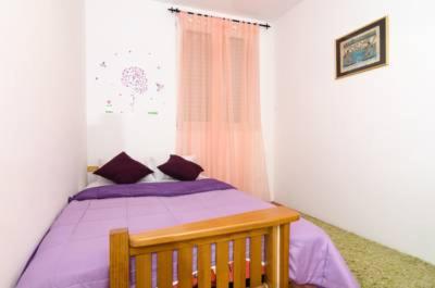 a bedroom with a bed with purple sheets and a window at Apartment Sara in Dubrovnik