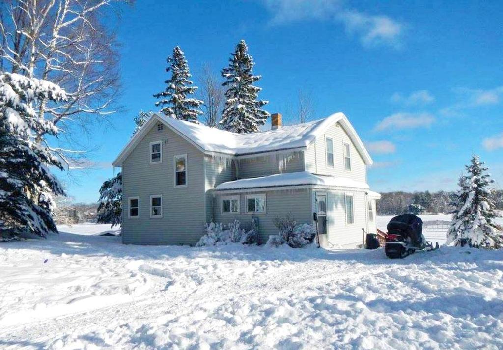 une maison dans la neige avec une moto devant dans l'établissement Spacious Cottage Rental with a Fire Pit and Fabulous Views in Summit Lake, Wisconsin, à Summit Lake
