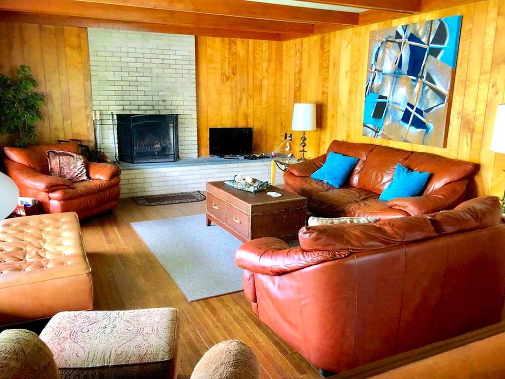 a living room with leather couches and a fireplace at Peaceful Private Cabin on Crystal Lake near Elk Mountain, Pennsylvania in Dundaff