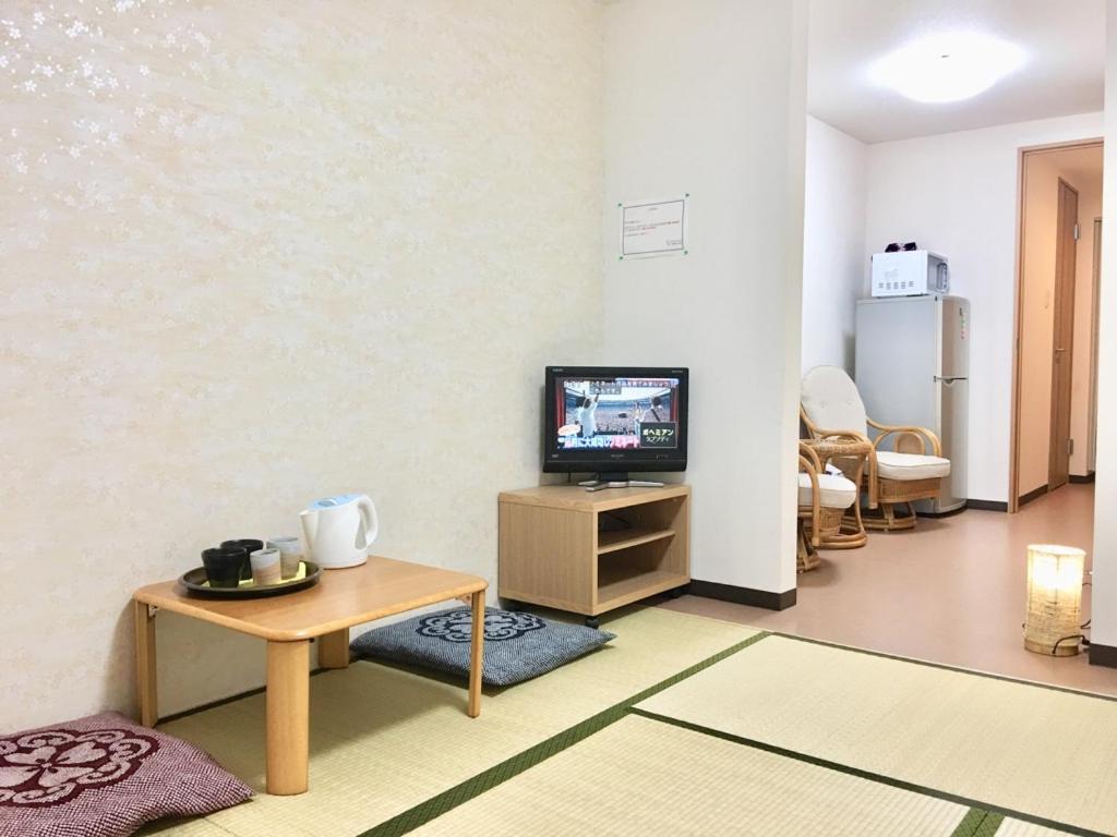 ein Wohnzimmer mit Fernseher und Tisch in der Unterkunft Osaka Tengachaya Guesthouse SAYURI 3号館 in Wada