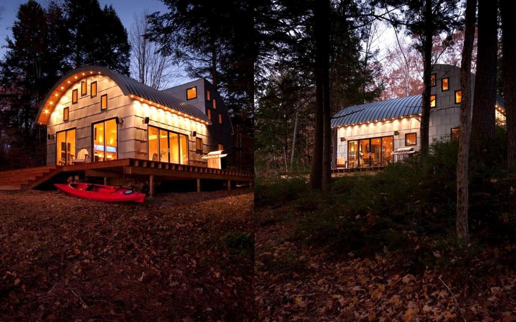a large house with a red boat in front of it at Unique Cottage Rental with Sublime Views Nestled on Damariscotta Lake in Maine in Jefferson