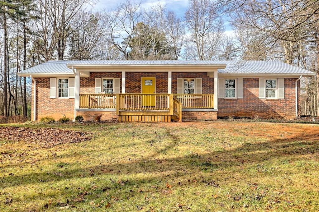 a brick house with a yellow door on a yard at Serene Cottage with Remodeled Interior and Gorgeous Pastures Views in Georgia in Shirley Grove