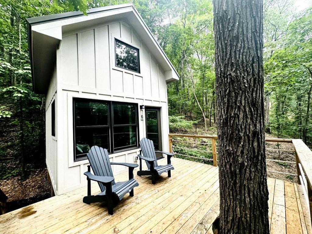 two chairs and a table on a deck with a tree at Off-grid Tree House Suitable for Four in Alabama in Grant