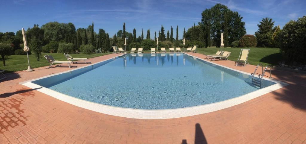 a large swimming pool with chairs in a park at Casa Terra Rossa in Fauglia