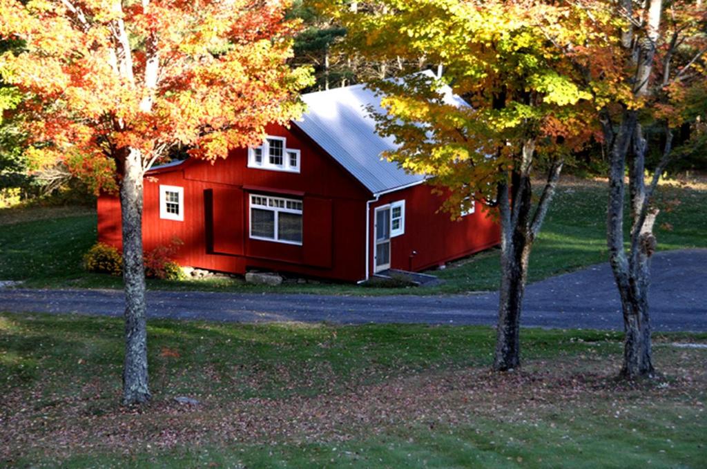 a red barn with trees in front of it at Light-Filled, Well-Appointed Mountain Cabin for a Vacation in Wells, Vermont in Wells