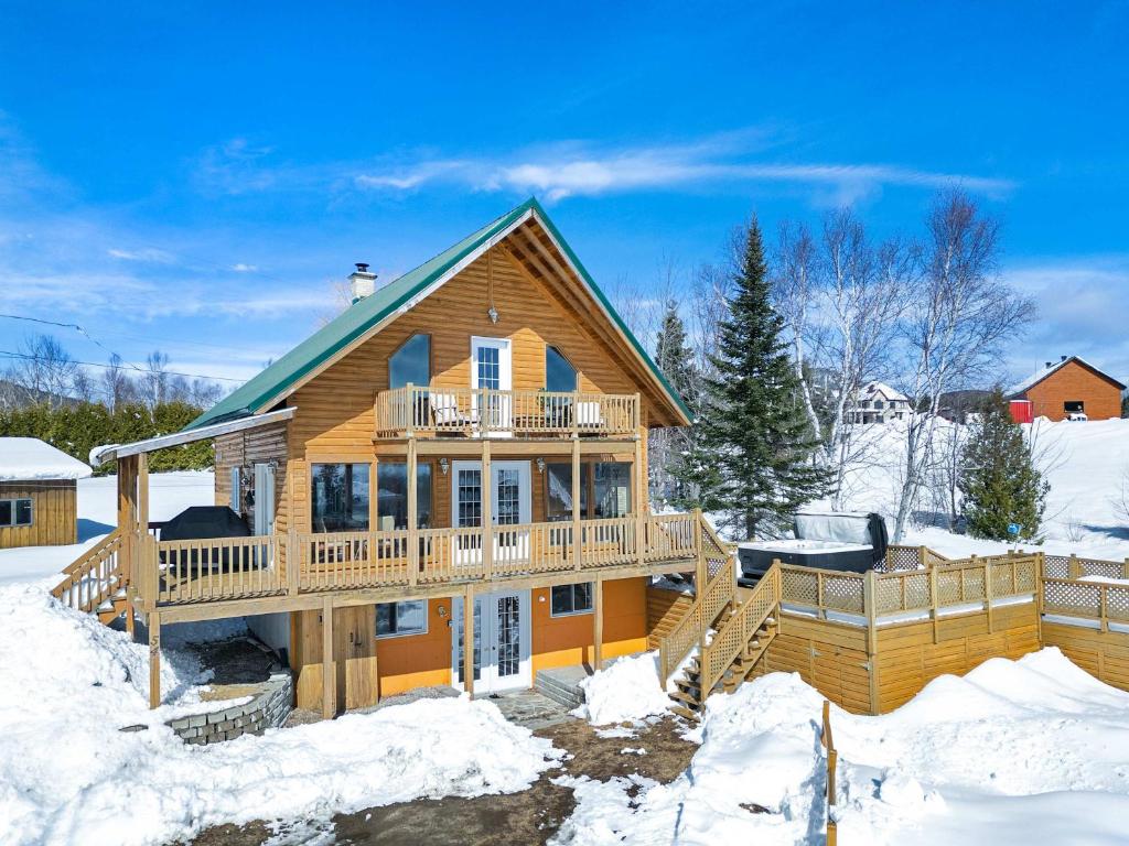 una casa de madera con terraza en la nieve en Spa Pool table Mountain view - Martine-54, en Petite-Rivière-Saint-François