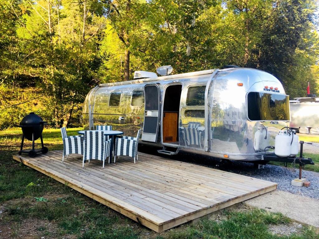 a trailer with a table and chairs on a wooden deck at Classy Airstream Land Yacht Rental with Modern Amenities near Gatlinburg, Tennessee in Shady Grove