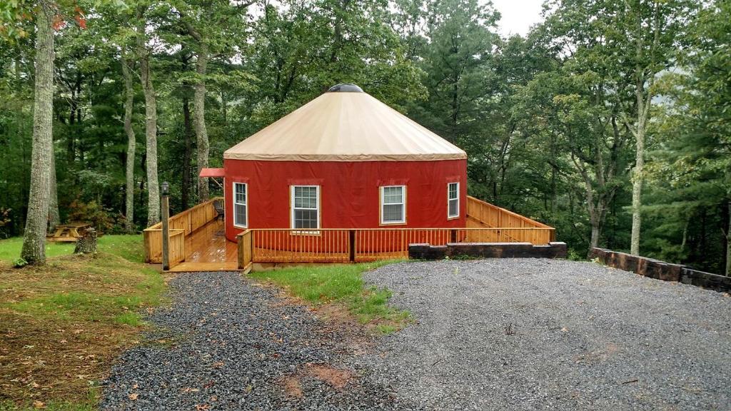 un bâtiment rouge avec un toit au milieu d'une cour dans l'établissement Gorgeous Yurt Rental for a River Vacation near Roanoke, Virginia, à Rich Creek