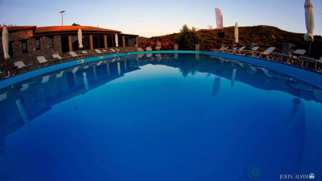 a large blue swimming pool with chairs and a building at Apollonion Hotel in Andritsaina