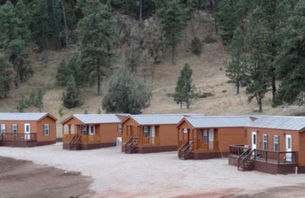 a row of wooden cabins in front of a mountain at Simple Weekend Getaway near the Black Hills Region of South Dakota in Sundance