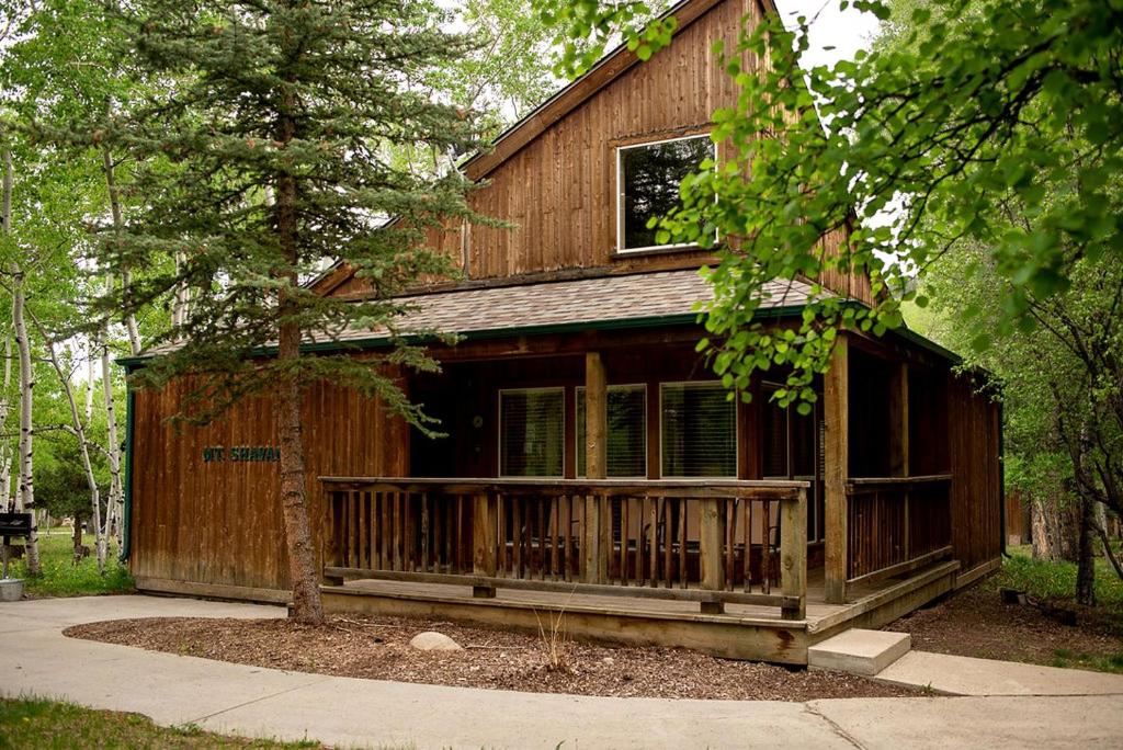 a wooden house with a porch and a tree at Beautiful Secluded Cabin with a Hot Tub near Monarch Mountain in Colorado in Monarch