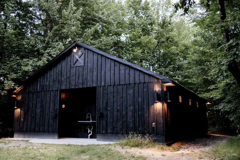 a black barn with a door with a cross on it at Outstanding Safari Tent with Fire Pit and Nice Sights in North Woodstock, New Hampshire in Woodstock
