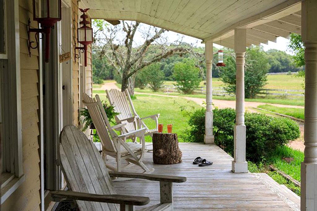 two rocking chairs on a porch with a tree stump at Romantic Country Getaway with Wood-Burning Fireplace near Houston, Texas in Cat Spring