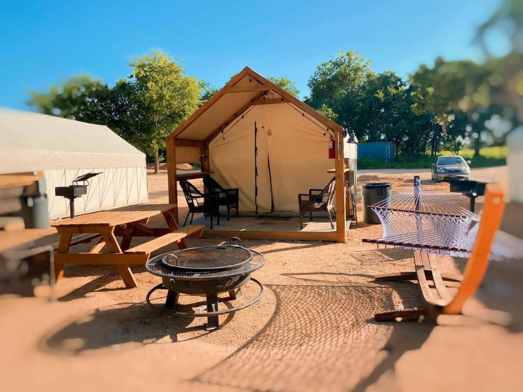 a tent with a grill and a table and chairs at Charming Safari Tent on the San Marcos River near Kingsbury, Texas - Perfect for an Aquatic Adventure in Staples