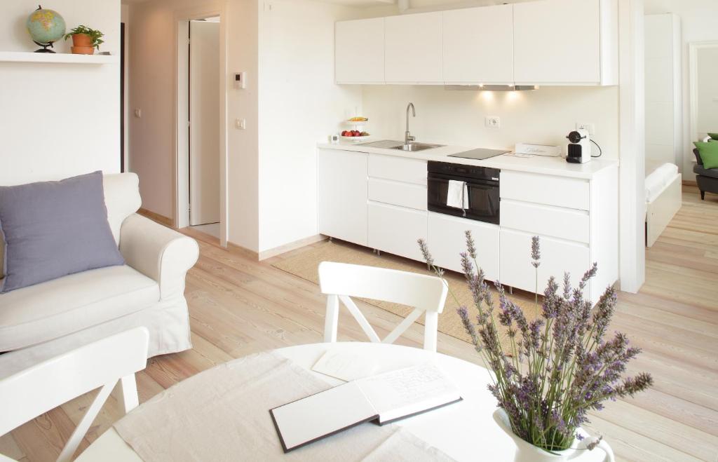 a white kitchen and living room with a couch and a table at The Riverside Suite in Mira